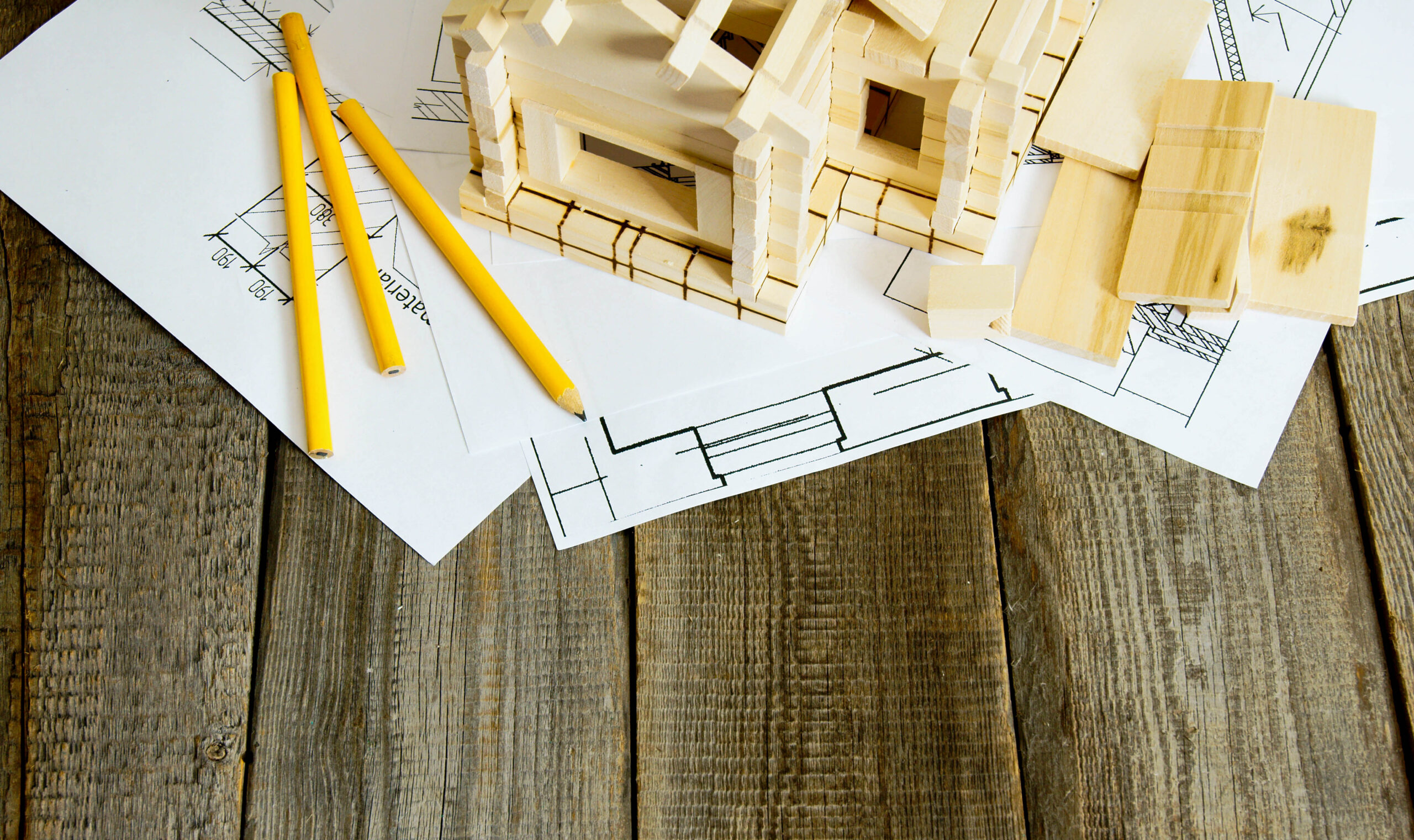Building house. House construction. Many drawings for building and wooden house on old wooden background.